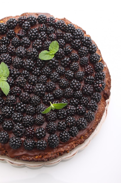 Torta de chocolate hecha en casa con las nueces y la zarzamora en el fondo blanco