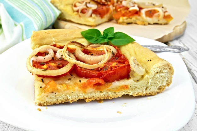 Torta com cebola e tomate em chapa branca na placa de luz