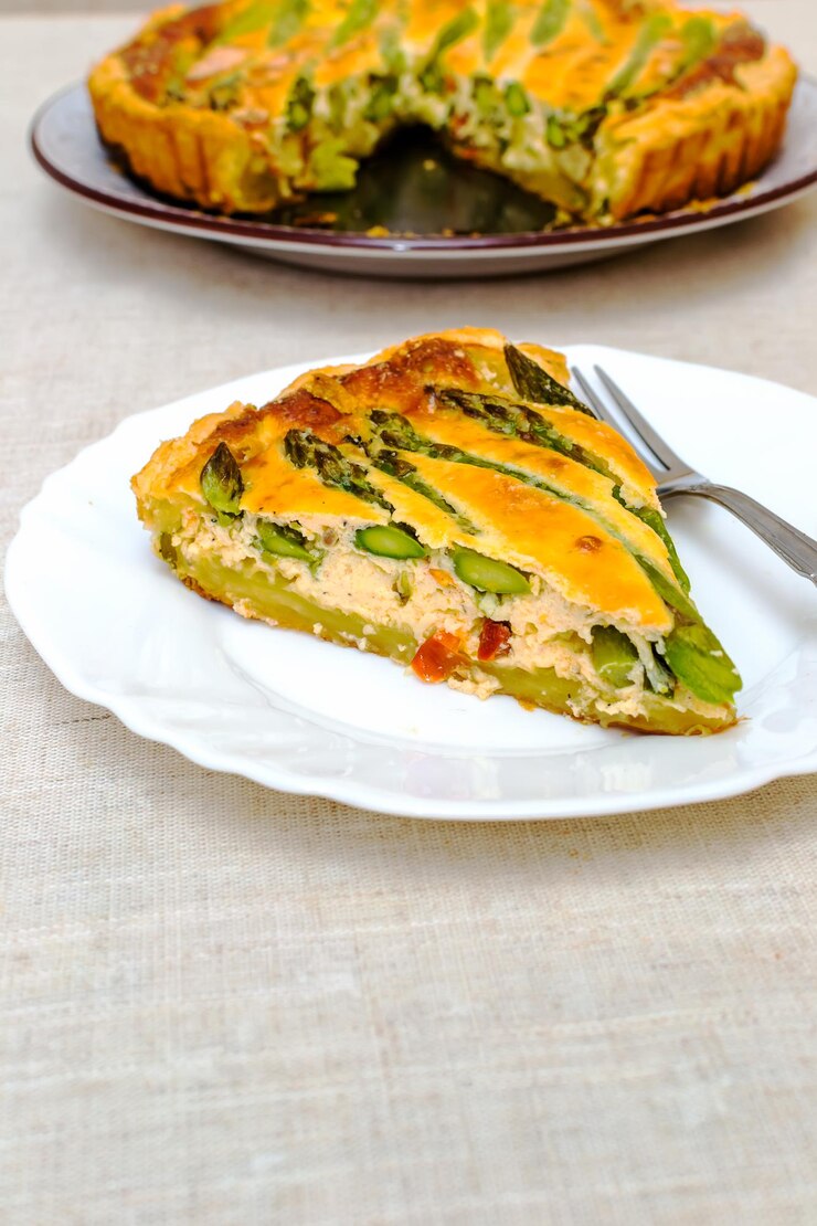 Foto torta com espargos verdes e queijo torrado na mesa.