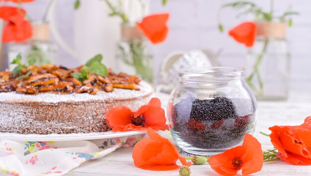 Torta com sementes de papoila em um fundo branco. Doces caseiros e flores vermelhas