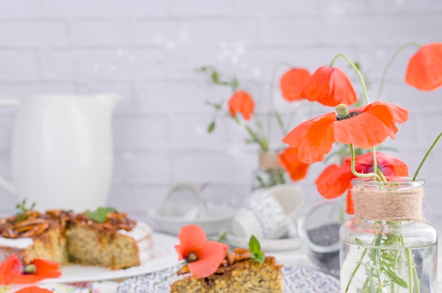 Torta com sementes de papoila em um fundo branco. Doces caseiros e flores vermelhas