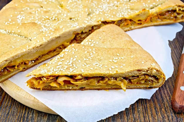 Torta com sementes de repolho e gergelim com massa de centeio em pergaminho e na placa de madeira de fundo