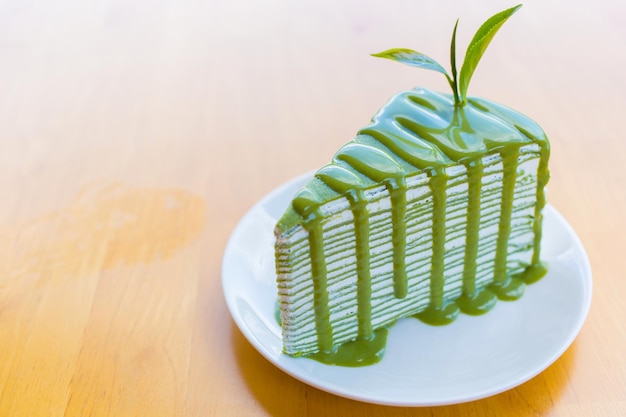 Torta de crepe de té verde matcha que en la parte superior con salsa de matcha y decorada con hojas frescas de té verde