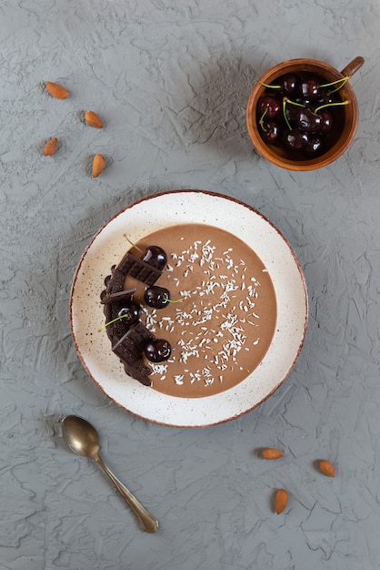 Torta cruda de chocolate vegano con cerezas sobre un fondo gris