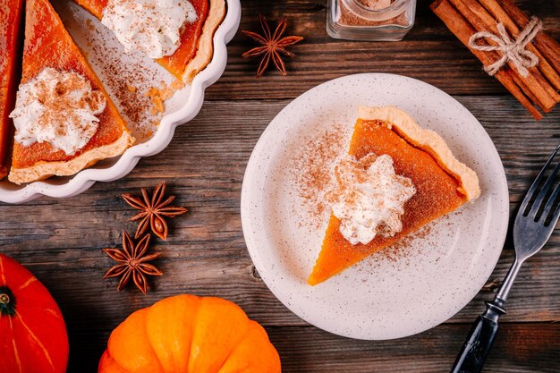 Torta de abóbora caseira para ação de Graças com chantilly e canela em fundo de madeira