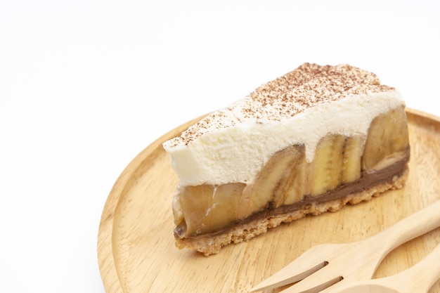 Torta de Banoffee, chantilly e banana na placa de madeira isolar fundo branco