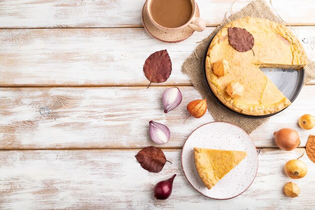 Torta de cebola de outono decorada com folhas e xícara de café na madeira branca