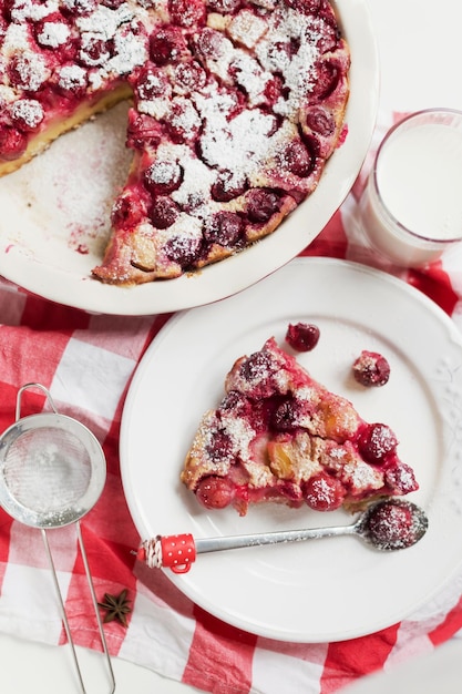 Torta de cereja com recheio de creme clafoutis de sobremesa francesa com pó de açúcar de cerejas vermelhas e colher engraçada Assadeira com torta saborosa