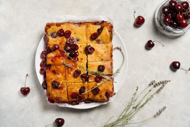 Torta de cereja doce assada fresca ou bolo de brownie vermelho no prato com lavanda e bagas cruas à parte