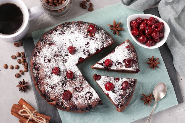 Torta de chocolate caseira com cerejas em um fundo cinza. vista de cima