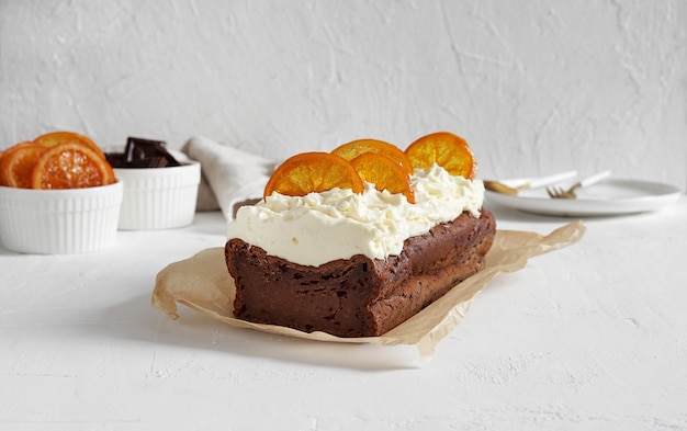 Torta de chocolate escura com creme e laranjas em foco seletivo de fundo de concreto claro