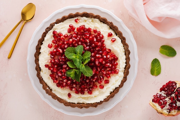 Torta de chocolate sobremesa caseira com creme de coco, romã e hortelã em uma mesa rosa