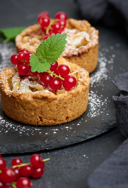 Torta de frutas com groselhas polvilhadas com açúcar em pó em uma deliciosa sobremesa de mesa preta