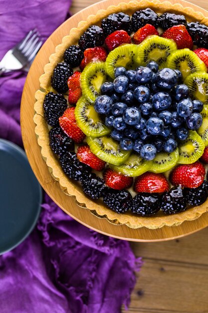 Torta de frutas frescas no carrinho de bolo na mesa de madeira.