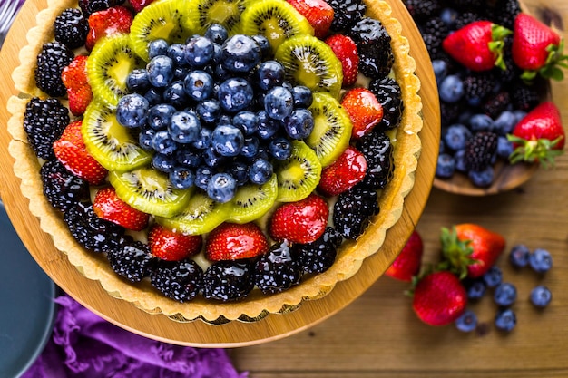 Torta de frutas frescas no carrinho de bolo na mesa de madeira.