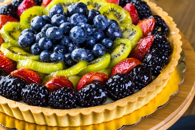 Torta de frutas frescas no carrinho de bolo na mesa de madeira.