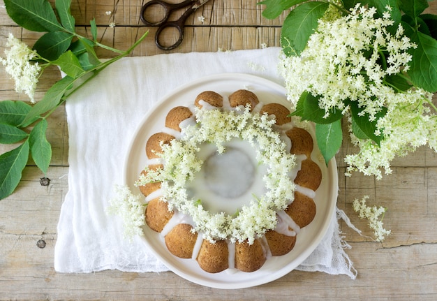 Torta de limão com cobertura de açúcar e xarope de sabugueiro, decorada com flores de sabugueiro. estilo rústico.