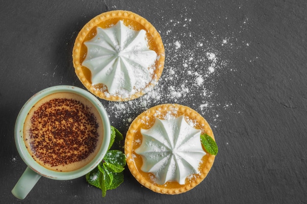 Torta de limão com folhas de hortelã e uma xícara de cappuccino com cobertura de chocolate