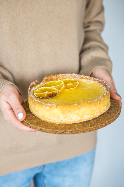 Foto torta de limão nas mãos de uma mulher com uma camisola de outono quente. conceito de cozimento em casa