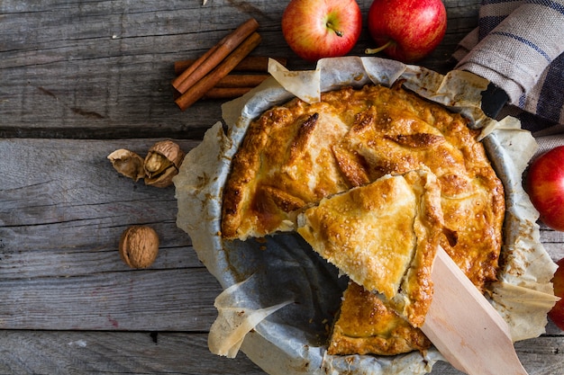 Torta de maçã com maçãs em fundo de madeira rústica