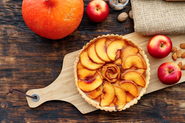 Torta de maçã e maçãs vermelhas na mesa de madeira