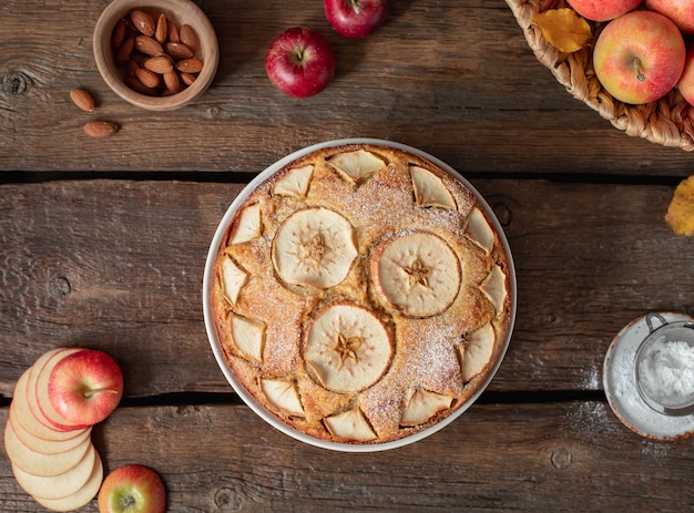 Torta de maçã em torno de maçãs, folhas, nozes em um rústico de madeira