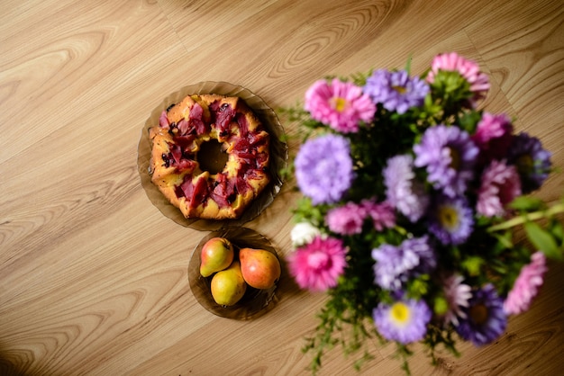 Torta de maçã, peras e flores em cima da mesa.