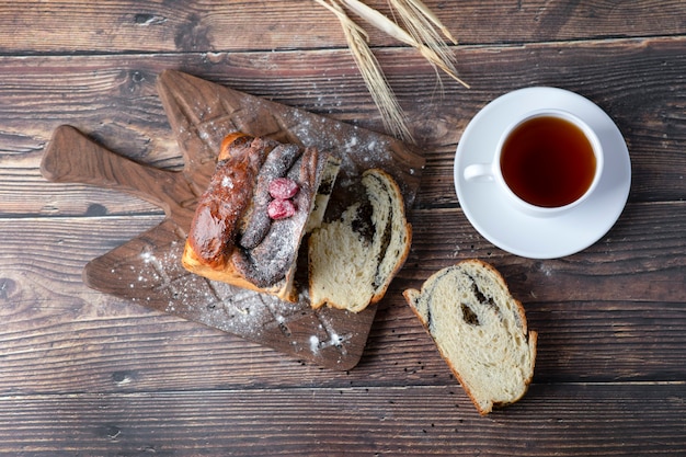 Torta de madeira com sementes de papoula e uma xícara de chá colocada sobre a mesa.