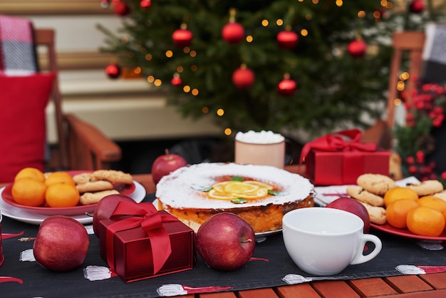 Torta de Natal, chocolate quente com marshmallows e mesa. Fundo da árvore de Natal. Reboque móvel de furgão, casa móvel, terraço. Celebração de Ano Novo. Férias de inverno. Manha de Natal.