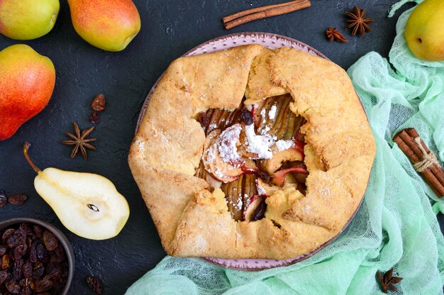 Torta de pêra caramelizada com canela e passas em um fundo preto