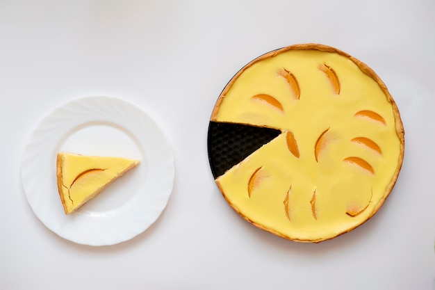 Torta de pêssego amarela com uma fatia cortada em um fundo branco