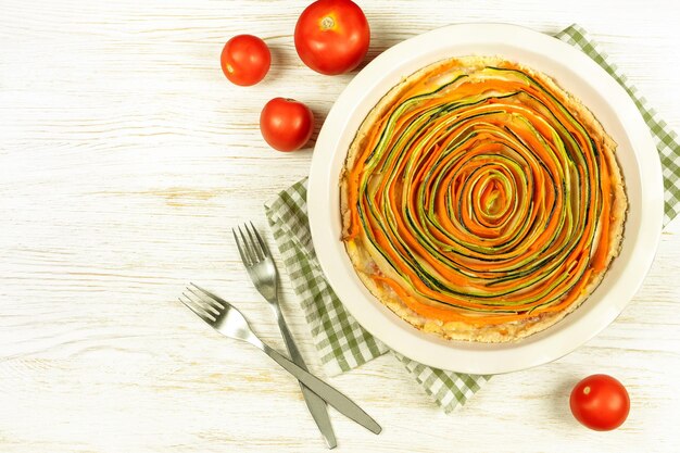 Torta de torta vegetal espiral caseira de cenouras abobrinha e berinjela em fundo branco de madeira