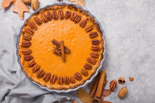 Torta e fatia de abóbora com porca de noz-pecã e canela no fundo concreto cinzento, vista superior, espaço da cópia. Pastelaria caseira de outono para o dia de ação de Graças