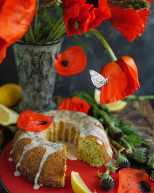 Torta encuadernada del limón y flores rojas hechas en casa. Mariposa voladora