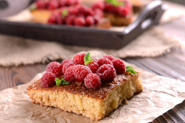 Torta fresca com framboesa em pergaminho em close de mesa de madeira