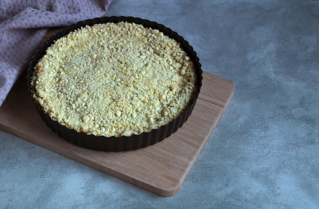 Torta friável com queijo cottage em forma preta em uma placa de madeira em um fundo cinza