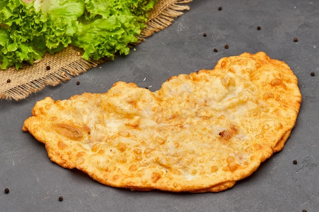 Torta frita cheburek com carne e cebola em fundo escuro de pedra comida insalubre prato tradicional de muitos povos turcos e mongóis