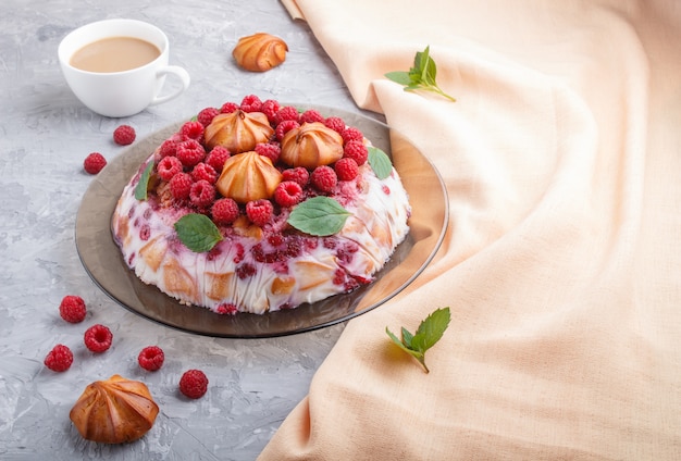 Torta de gelatina casera con leche, galletas y frambuesa sobre una superficie de hormigón gris con taza de café y textil naranja, vista lateral.