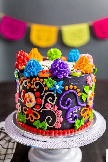 Torta gourmet del Día de los Muertos decorada con colorido glaseado de crema de mantequilla y toppers de cupcakes gomosos.