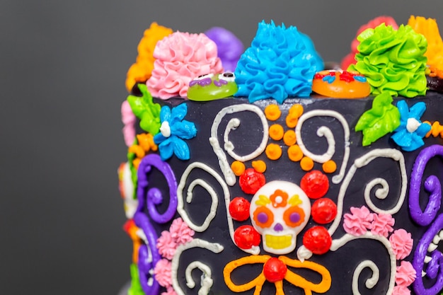 Foto torta gourmet del día de los muertos decorada con colorido glaseado de crema de mantequilla y toppers de cupcakes gomosos.