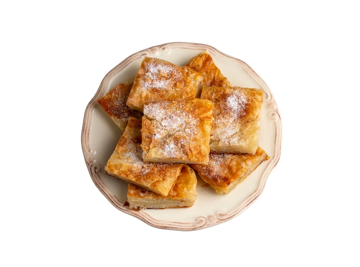 Foto torta grega chamada bougatsa com queijo, seção transversal ligeiramente desfocada e foco seletivo em açúcar em pó e canela