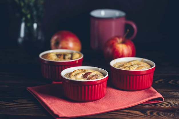 Torta de manzana en moldes de horneado de cerámica ramekin en una mesa de madera oscura cerrar la profundidad poco profunda del campo desayuno romántico o cena con café