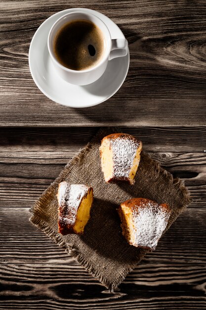 Torta na cama com a xícara de café em um fundo de uma mesa de madeira