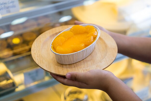 Torta de naranja en placa de madera en la mano