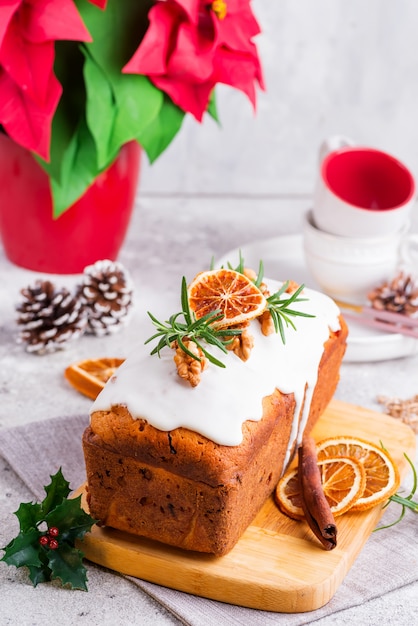 Torta de pan de fruta espolvoreada con glaseado, nueces y naranja seca sobre piedra. Pastel casero de Navidad e Invierno