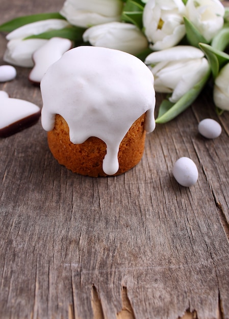 Torta de Pascua, tulipanes blancos, conejito del chocolate y huevos en un fondo de madera. Copia espacio