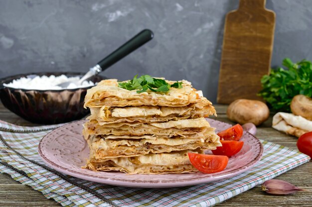 Torta, pita caçarola com cogumelos, queijo cottage e queijo num prato sobre um fundo de madeira. bolo de camadas.