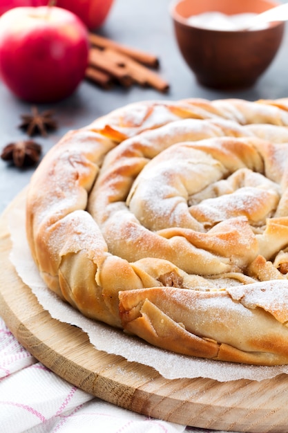 Torta redonda de burek com uma maçã em um fundo escuro. Cozinha tradicional sérvia. Foco seletivo. Vista do topo.