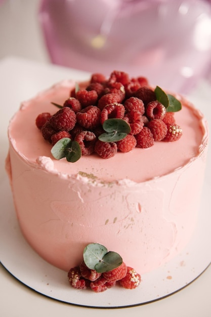 Torta rosa festiva con frambuesas en el fondo de globos de helio de corazones rosas