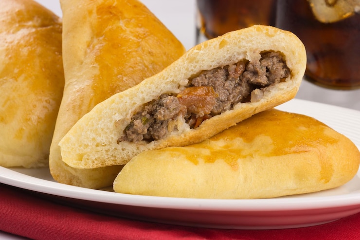 Foto torta sírio-libanesa recheada com carne chamada sfiha com uma aberta em uma bandeja em fundo branco